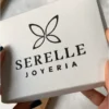 Packaging de Regalo Serelle Joyería Manos sosteniendo la caja de regalo blanca de Serelle Joyería, ideal para presentar accesorios de acero dorado y sets de joyas para mujer.