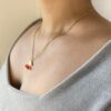 Collar Fino Cereza en Modelo Detalle del collar de acero dorado con dije de cereza puesto en el cuello de una modelo, vista en ángulo mostrando la delicadeza de la cadena.