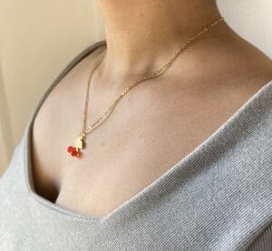 Collar Fino Cereza en Modelo Detalle del collar de acero dorado con dije de cereza puesto en el cuello de una modelo, vista en ángulo mostrando la delicadeza de la cadena.