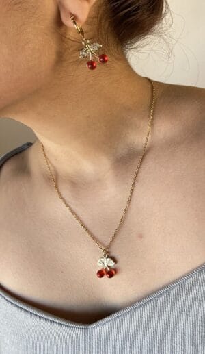 Collar Cereza de Acero Dorado en Uso Vista frontal de una mujer usando el collar de acero quirúrgico dorado del set de joyas Cereza, destacando cómo cae el dije sobre el pecho.