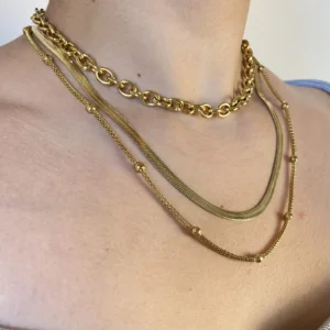 Set Collares Dorados en Capas en Modelo Set de tres collares dorados de acero quirúrgico en capas, lucido por una mujer.