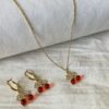 Portada Set Collar y Aros Cereza Set de joyas para mujer de acero dorado hipoalergénico, mostrando el collar y los aros con dijes de cereza sobre una tela de lino blanco.