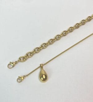 Detalle Cierres y Dije Combo Rustik-dropCuadros Detalle de los dos collares de acero dorado del set Rustik-dropCuadros en una superficie blanca, mostrando sus cierres de mosquetón y el dije de gota.