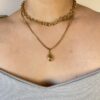 Combo Rustik y Dije Gota en Modelo (Frontal) Vista frontal de una modelo luciendo el set de dos collares de acero dorado: el choker Rustik y el collar con dije de gota, creando un efecto layering.