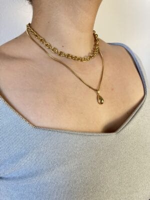 Look con Combo de Collares Dorados (Ángulo 2) Segundo ángulo lateral de una modelo con el combo de collares de acero dorado, mostrando cómo se asientan las dos piezas en el cuello y el escote.