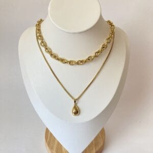 Portada Combo X2 Collares Rustik y Dije Gota Portada del set de dos collares de acero dorado para mujer, con el choker Rustik y el collar con dije de gota, exhibidos en un busto de joyería.