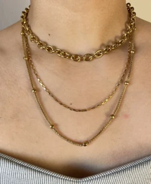 Combo X3 Collares Dorados en Modelo (Frontal) Modelo usando de frente el combo de tres collares de acero quirúrgico dorado, mostrando el efecto layering de las cadenas Rustik, Rectangles y Elegant.