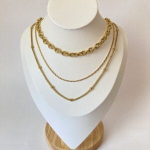 Portada Combo X3 Collares Rustik Rectangles Elegant Portada del combo de tres collares de acero dorado para mujer, perfectamente dispuestos en capas sobre un busto de exhibición blanco.