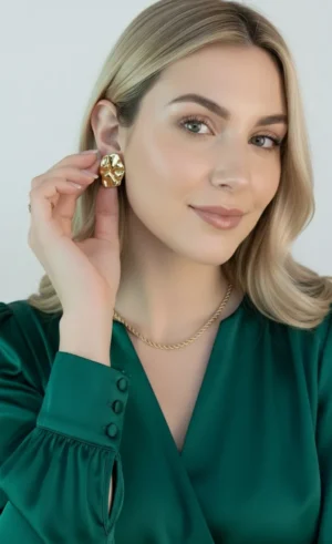 Aros Dorados en Uso Mujer rubia colocándose un aro chunky dorado en la oreja.
