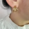 Aros Triple Argolla en Modelo Mujer luciendo los aros de triple argolla dorada de acero quirúrgico.