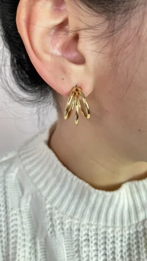 Aros Triple Argolla en Modelo Mujer luciendo los aros de triple argolla dorada de acero quirúrgico.