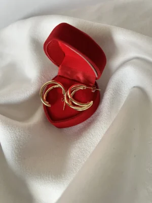 Aros Triple Argolla para Regalo Aros de triple argolla dorada dentro de un estuche de regalo rojo de terciopelo.