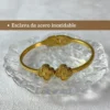 Esclava de Acero Inoxidable Pulsera esclava de acero inoxidable dorada con tréboles y vista del cierre de bisagra.