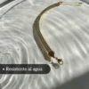 Joya de Acero Resistente al Agua Pulsera de acero quirúrgico dorado sobre una superficie de agua para demostrar su resistencia.