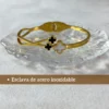Diseño Moderno en Acero Inoxidable Pulsera esclava de acero inoxidable dorado con tréboles sobre una base de vidrio transparente.