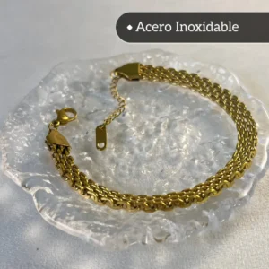 Pulsera Dorada de Malla Plana - Vista Completa Pulsera de acero inoxidable dorado con tejido de malla plana sobre una base de cristal.
