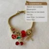 Características Pulsera Charms Dorada Infografía de la pulsera con charms dorados detallando su material, peso, largo y grosor.