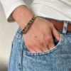 Look Casual con Pulsera Esclava Vista de la pulsera esclava dorada con strass en la muñeca de una mujer con jean y remera blanca.