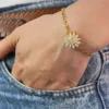 Pulsera Girasol Dorada en Muñeca Vista de la pulsera de girasol dorada en la muñeca de una mujer con la mano en el bolsillo de un jean.