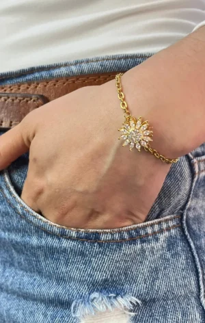 Pulsera Girasol Dorada en Muñeca Vista de la pulsera de girasol dorada en la muñeca de una mujer con la mano en el bolsillo de un jean.
