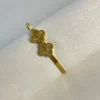 Detalle Tréboles Pulsera de Acero Detalle del doble trébol de la pulsera dorada sobre una superficie texturizada.