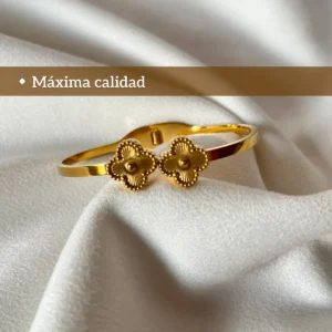 Pulsera Esclava Trébol Dorada ista frontal de la pulsera esclava dorada con diseño de doble trébol sobre una tela blanca.