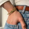 Pulsera Trébol en Uso Mujer usando la pulsera esclava de trébol dorado con jeans y un top blanco.