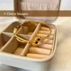 Cierre de Bisagra Práctico y Seguro Pulsera de acero dorado mostrando su cierre de bisagra abierta, apoyada en un alhajero.